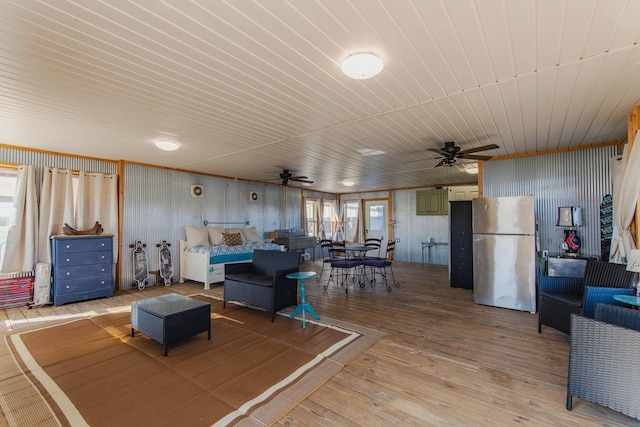 living room with ceiling fan, wooden walls, and light hardwood / wood-style flooring