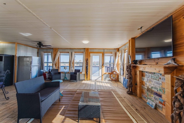 living room featuring wooden walls, ceiling fan, and hardwood / wood-style flooring