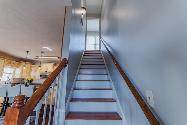 stairway featuring a textured ceiling