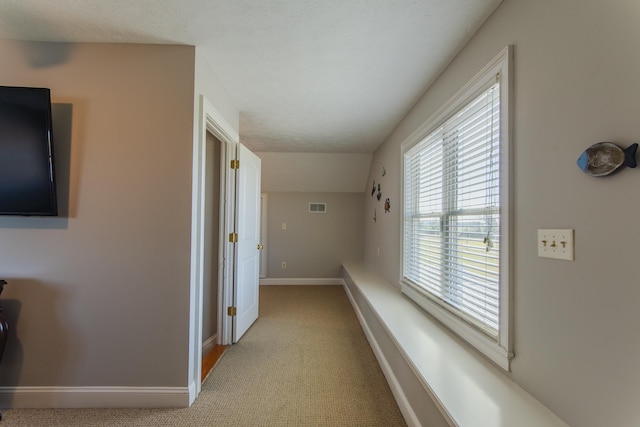 corridor featuring a textured ceiling and light carpet