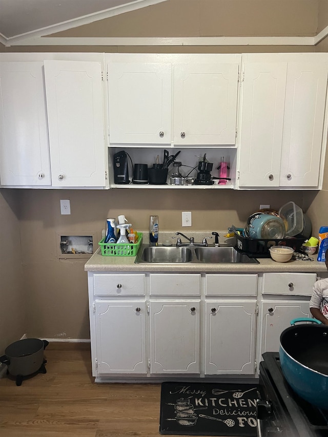 kitchen featuring white cabinetry, sink, vaulted ceiling, and hardwood / wood-style flooring