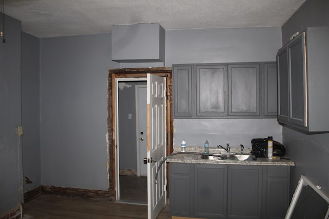 kitchen with gray cabinetry, sink, dark wood-type flooring, and a textured ceiling