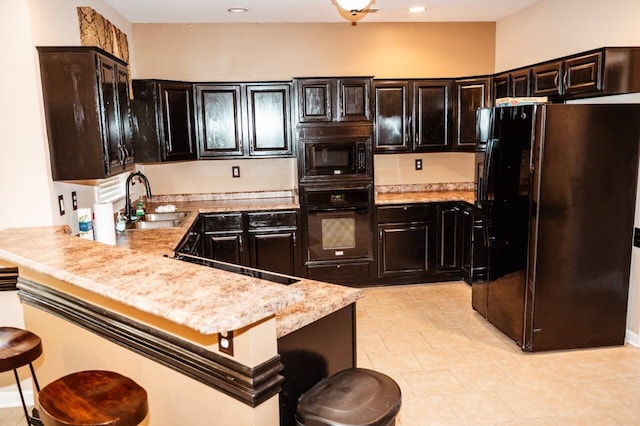 kitchen featuring kitchen peninsula, a kitchen bar, light stone counters, sink, and black appliances