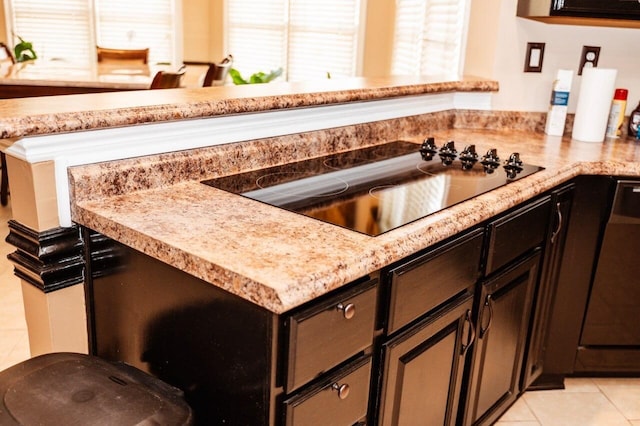 kitchen featuring dark brown cabinetry, black electric cooktop, and light tile patterned floors