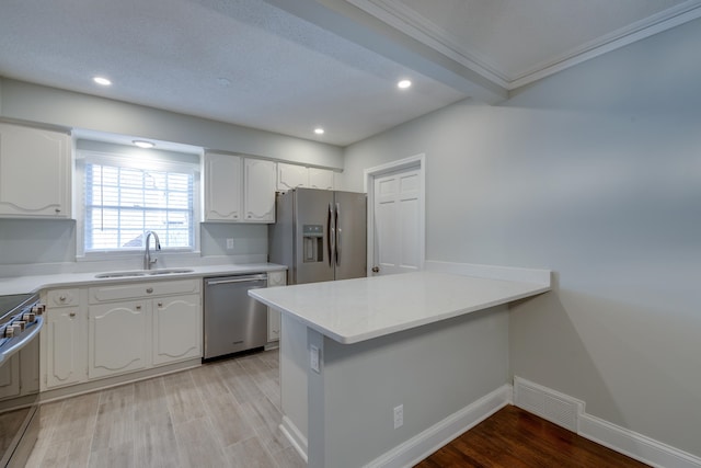 kitchen with light wood-type flooring, white cabinetry, sink, and appliances with stainless steel finishes