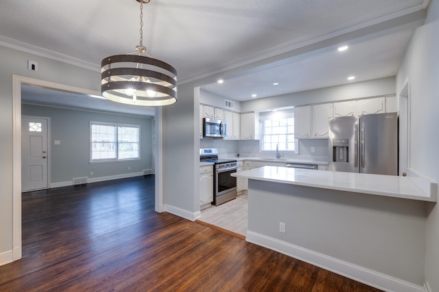 kitchen with dark hardwood / wood-style flooring, stainless steel appliances, white cabinetry, and plenty of natural light