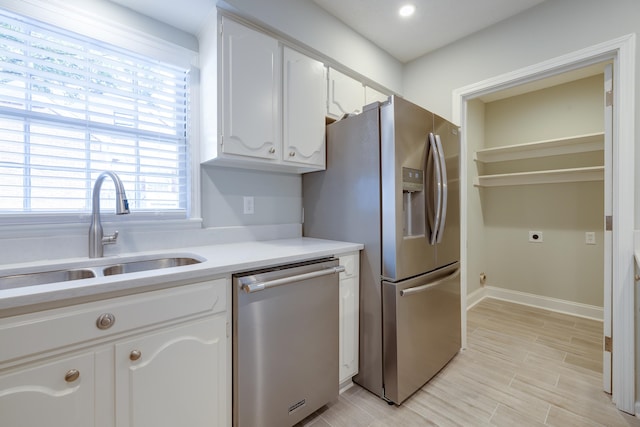 kitchen with white cabinets, stainless steel appliances, light hardwood / wood-style flooring, and sink