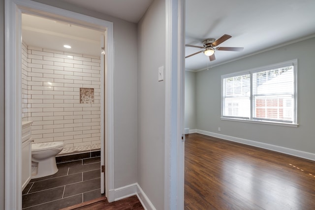 bathroom with hardwood / wood-style flooring, ceiling fan, toilet, ornamental molding, and a tile shower