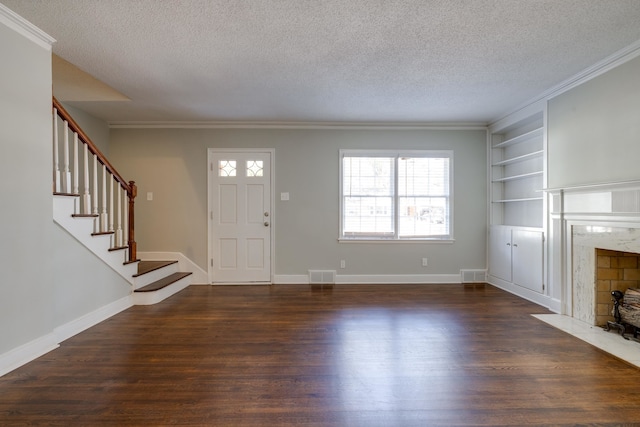 foyer with a premium fireplace, dark wood-type flooring, a textured ceiling, and ornamental molding