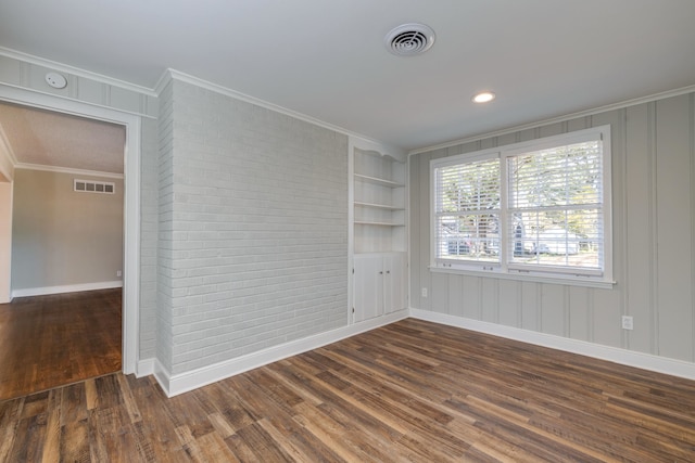 spare room with built in features, ornamental molding, and dark wood-type flooring