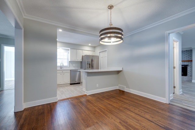 kitchen with white cabinets, light hardwood / wood-style floors, kitchen peninsula, and stainless steel appliances