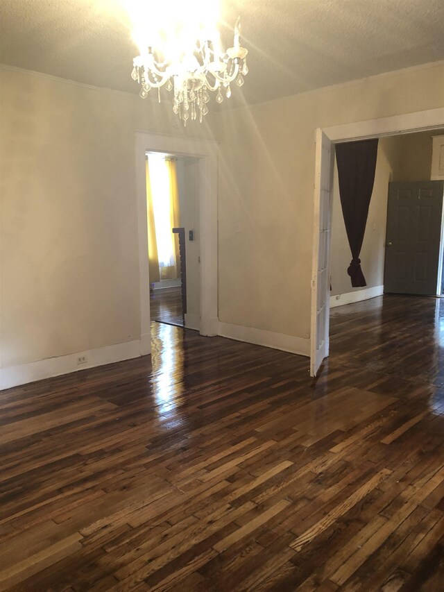 interior space with dark wood-type flooring, a textured ceiling, and an inviting chandelier