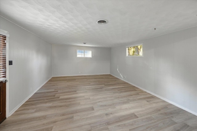 basement featuring a textured ceiling, light hardwood / wood-style floors, and a healthy amount of sunlight