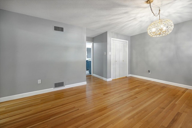 spare room featuring hardwood / wood-style floors, a notable chandelier, and a textured ceiling