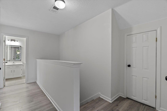 hall with light hardwood / wood-style floors and a textured ceiling