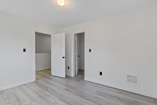 unfurnished room with a textured ceiling and light hardwood / wood-style flooring