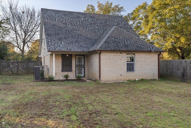 rear view of house featuring central air condition unit and a lawn