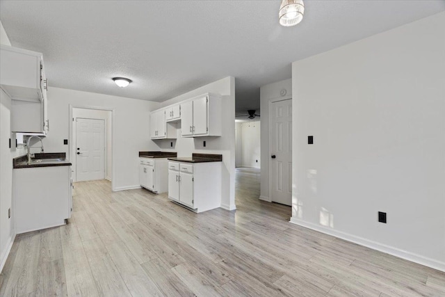 kitchen featuring sink, ceiling fan, light wood-type flooring, a textured ceiling, and white cabinetry