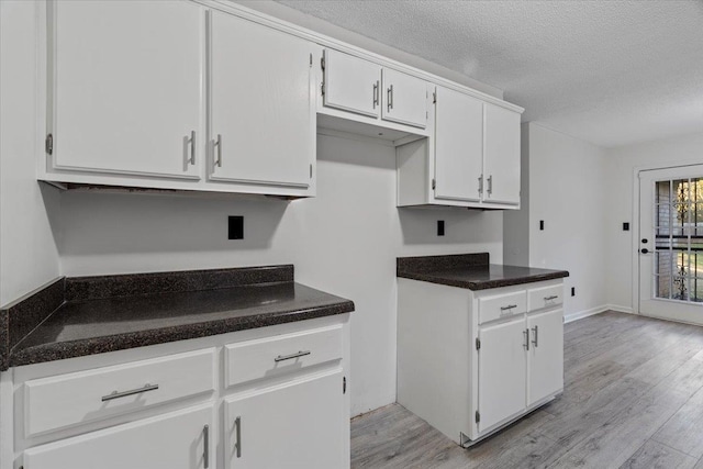 kitchen with white cabinets, light wood-type flooring, and a textured ceiling