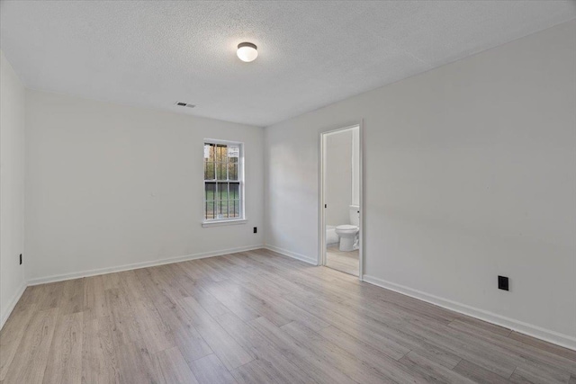 spare room featuring light hardwood / wood-style flooring and a textured ceiling