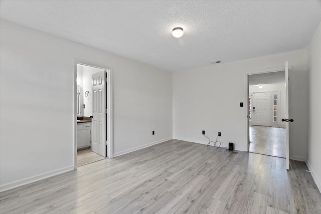 unfurnished room with light wood-type flooring and a textured ceiling