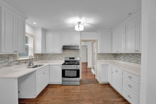 kitchen with decorative backsplash, stainless steel gas range oven, dark wood-type flooring, sink, and white cabinetry