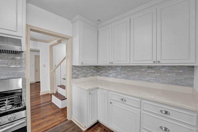 kitchen with dark hardwood / wood-style floors, stainless steel range oven, white cabinetry, and backsplash