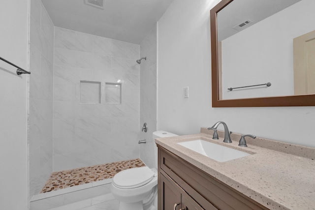 bathroom featuring tiled shower, tile patterned floors, vanity, and toilet