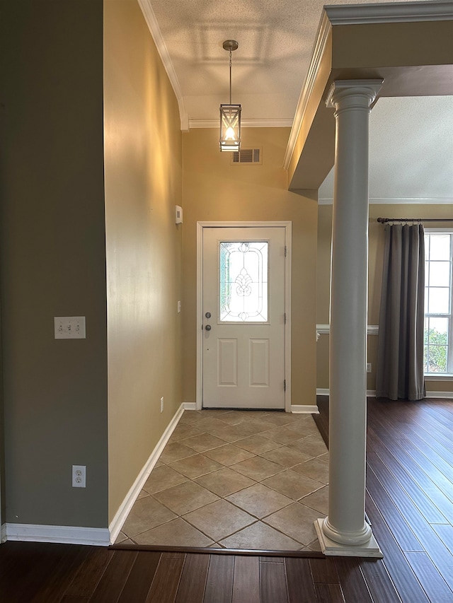 foyer entrance with hardwood / wood-style floors, ornamental molding, a textured ceiling, and decorative columns