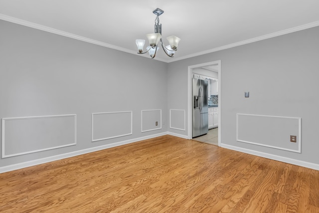 empty room with an inviting chandelier, crown molding, and light hardwood / wood-style flooring