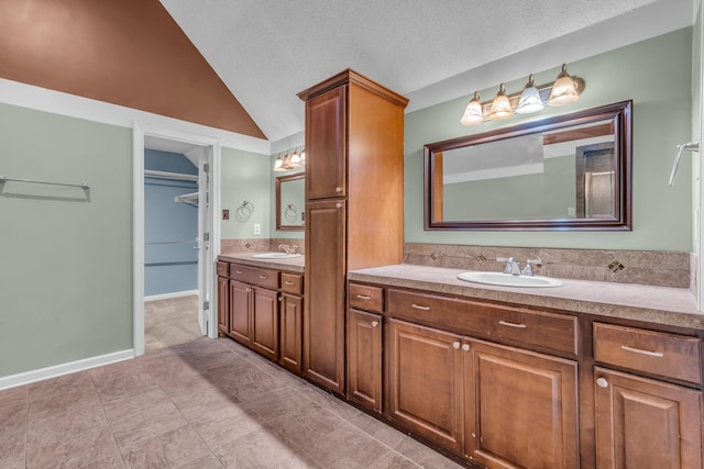 bathroom with vanity, tile patterned floors, a textured ceiling, and vaulted ceiling