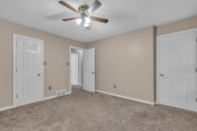 unfurnished bedroom with ceiling fan, light colored carpet, and a textured ceiling