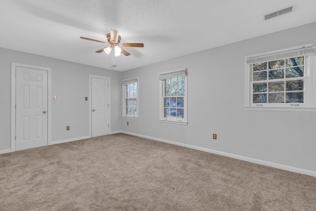 empty room featuring ceiling fan, carpet floors, and a textured ceiling