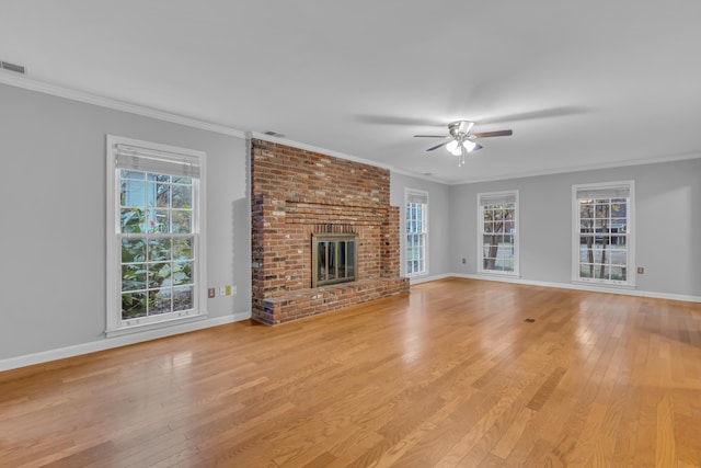 unfurnished living room with a fireplace, light hardwood / wood-style floors, a wealth of natural light, and ornamental molding