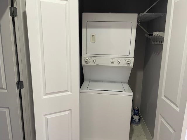 washroom featuring laundry area, stacked washer and clothes dryer, and baseboards