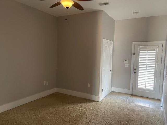 empty room featuring light carpet, baseboards, visible vents, and ceiling fan