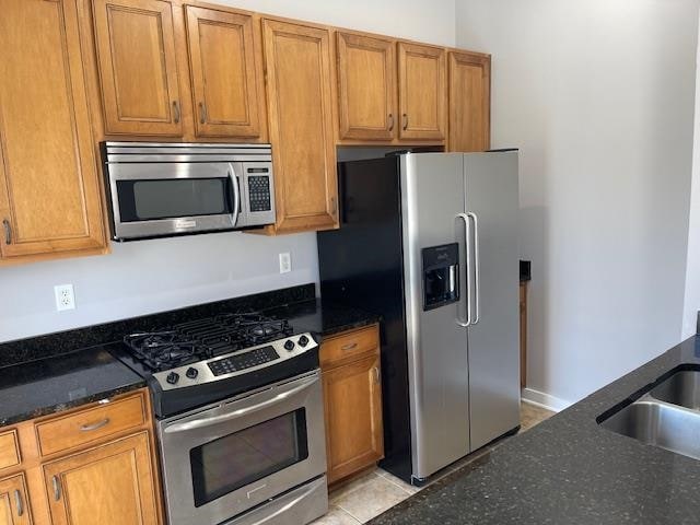 kitchen with stainless steel appliances, brown cabinetry, and a sink