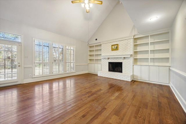 unfurnished living room with built in shelves, ceiling fan, high vaulted ceiling, a fireplace, and hardwood / wood-style flooring