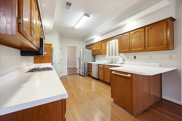 kitchen featuring kitchen peninsula, light hardwood / wood-style floors, stainless steel appliances, and crown molding