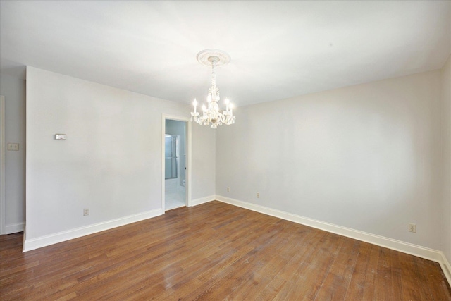 spare room featuring hardwood / wood-style flooring and a chandelier