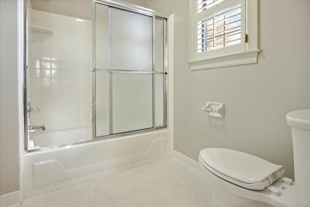 bathroom featuring tile patterned floors, toilet, and bath / shower combo with glass door