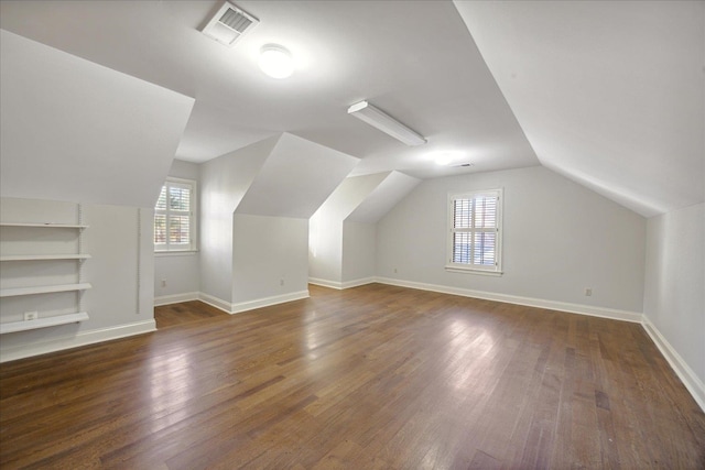 additional living space with dark hardwood / wood-style floors, built in features, plenty of natural light, and lofted ceiling