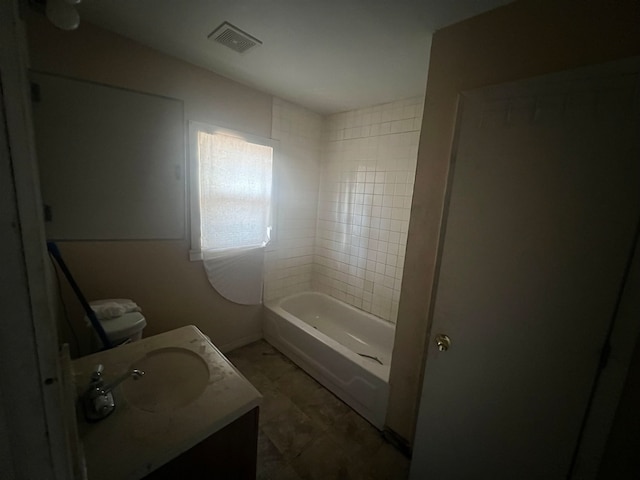 full bathroom with vanity, tiled shower / bath combo, and toilet