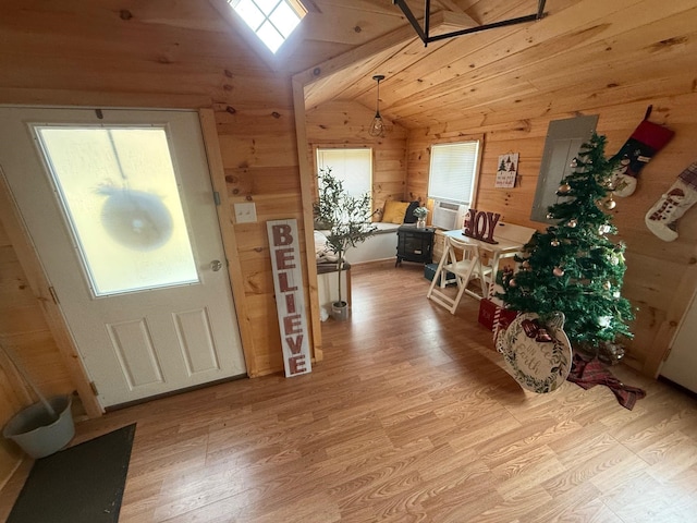 entryway with light hardwood / wood-style floors, vaulted ceiling, a healthy amount of sunlight, and wood walls