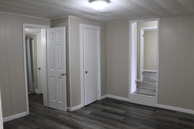 unfurnished bedroom featuring wooden walls and dark wood-type flooring