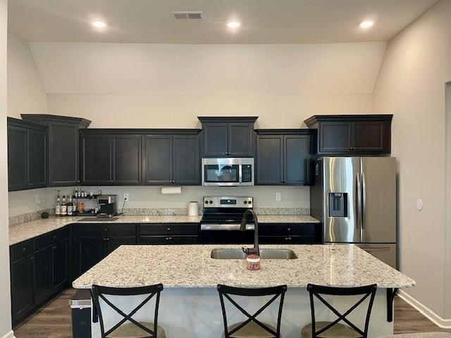 kitchen with stainless steel appliances, a kitchen island with sink, a breakfast bar area, and sink