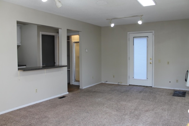 unfurnished living room with carpet flooring and rail lighting