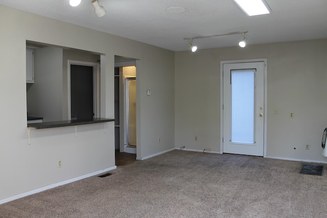 carpeted empty room with a textured ceiling and track lighting