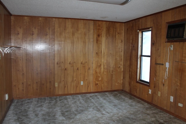 carpeted empty room with a textured ceiling and wooden walls