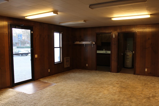 empty room with light carpet, wooden walls, and water heater